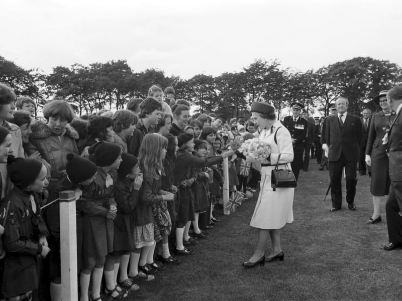 Queen Elizabeth II stops to chat and accept flowers from some Brownies during a Royal visit to Livingston in July 1978.