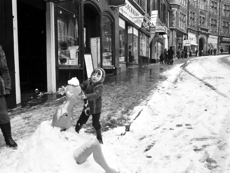 Four-year-old Keith Newton puts the finishing touches to his snow-woman - made from a mannequin - in Cockburn Street Edinburgh, February 1978.