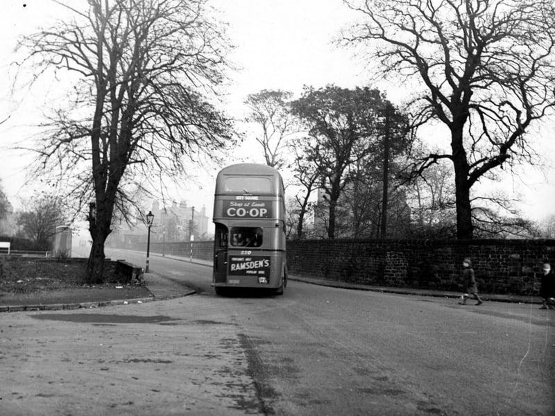 Looking east at the junction of Kirkstall Lane and Queenswood Drive. A bus for City Square drives away with advertisements for Leeds Co-op and Ramsdens. Two boys cross the road on the right. Pictured in October 1949.