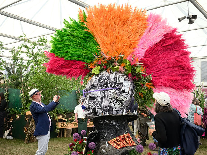 A visitor stops to photograph a floral display by Ricky Paul Flowers in the form of a punk's mohican hairstyle.