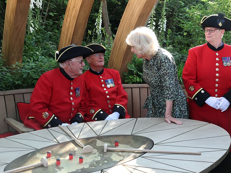 Queen Camilla speaks with Chelsea Pensioner members, at the London Square Chelsea Pensioners Garden.