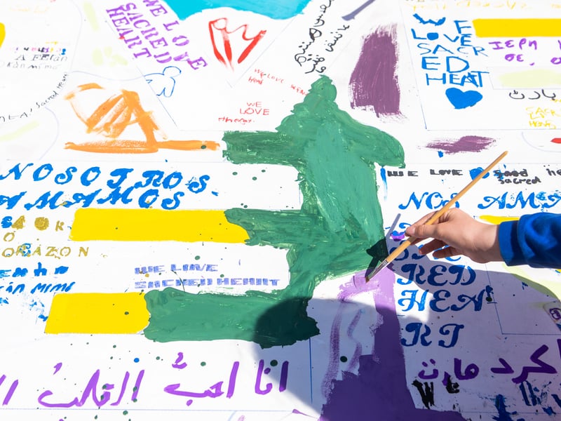 Children will translate the phrase “We Love Sacred Heart” into their home languages, reflecting the many backgrounds and stories represented within the school.