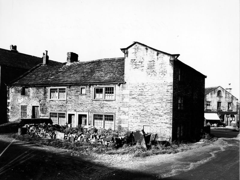 The rear of old cottages behind a dry stone wall on Town Street in October 1950. A bicycle and a pram outside a shop can be seen in the background. 
