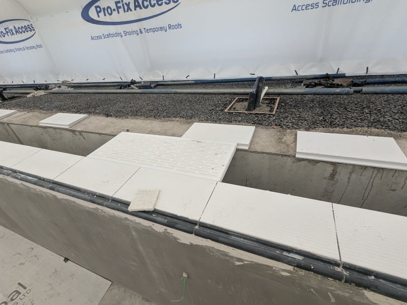 The team have started putting horizontal tiles around the edge of the pool, along with the black finger rests. Next, they will put the horizontal tiles on the other side of the drainage gulley.