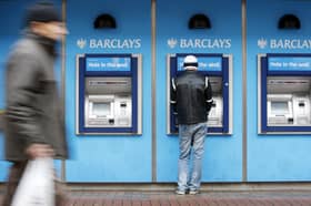 A man uses a cashpoint machine at a Barclays Bank 