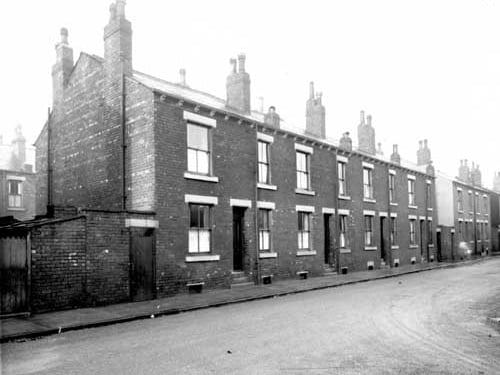 Row of back-to-back terrace houses on Toft Street, off Oldfield Lane. To the left yard housing outside toilets and dustbins. Pictured in December 1938.