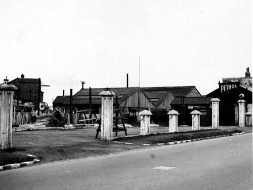 The premises of W H Calvert, City Petrol Co. of Whitehall Road showing deserted forecourt. Beyond the wooden fence at the back of several industrial buildings. Pictured in April 1937.