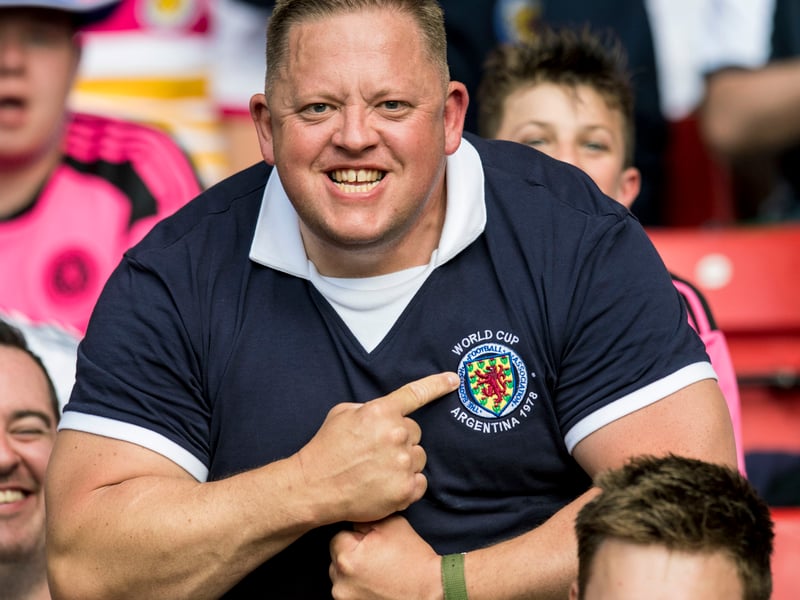 This Scotland fans point at the badge on his shirt to show his support the team.