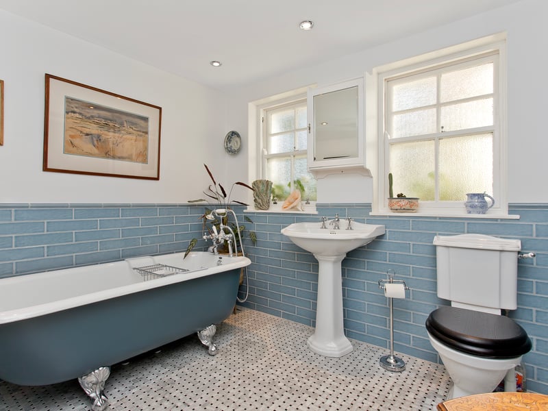 The family bathroom is beautifully styled with blue wall tiles and featuring a freestanding, cast iron roll-top bathtub with a traditional shower attachment, a large shower enclosure, and a WC-suite. The shower room and bathroom both have underfloor heating.