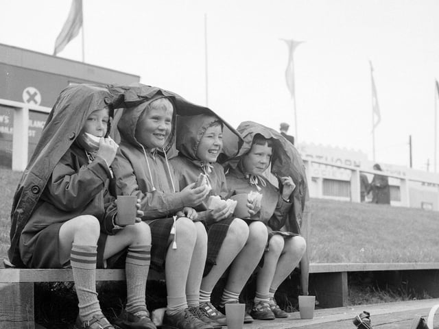 David Fisher, Fiona Armstrong, Mary Fisher and Lisa Fisher from Plean Mill. near Stirling, enjoy their packed lunches under a plastic mac at the Highland Show in 1965.