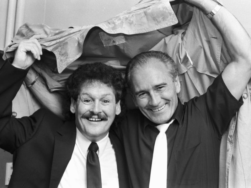 Sheltering under a raincoat, Tommy Cannon (white tie) and Bobby Ball aka Cannon & Ball, who were appearing in "You'll Do For Me" at the Kings theatre in Edinburgh, 1989