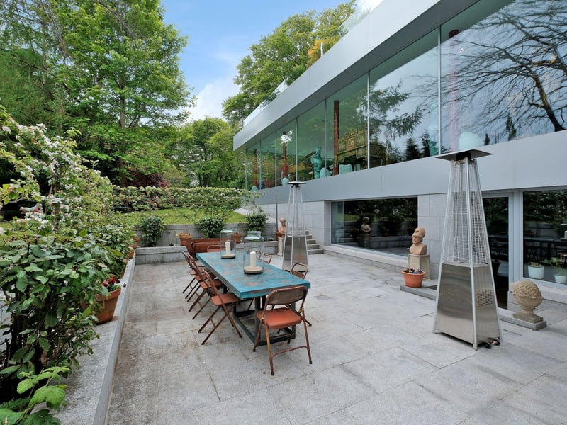 Featuring a dining table and outdoor heater with access to the home gym, the lower patio.