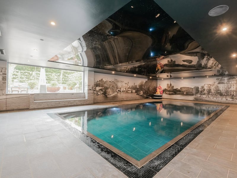 The large indoor swimming pool is surrounded by a mural with views into the garden.