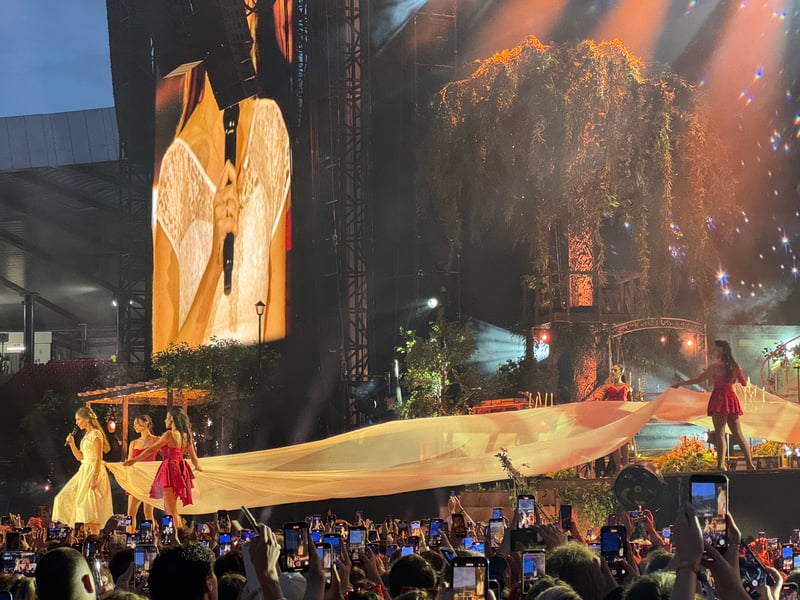 Lana Del Ray walks into the crowd wearing a long bridal train.