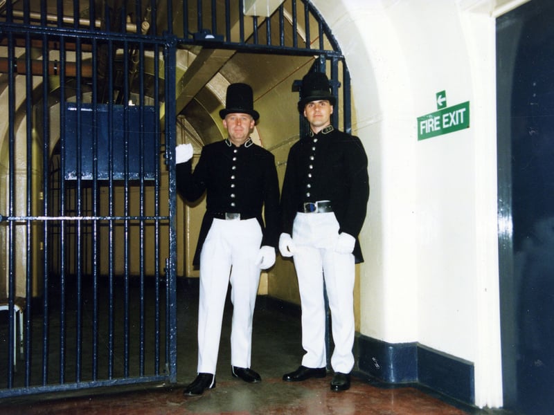 Two men model the first uniforms of the Leeds Borough Police. They were adapted from designs of the London Metropolitan Police. Dark blue serge jackets were worn, with tails and high tunic collar. The white 'duck' trousers were worn during the summer months and dark blue serge trousers were the winter alternative. A black leather belt was buckled at the waist with a metal buckel engraved with the Leeds fleece. The tall black leather top hat was known as a 'stove pipe' and the top was laquered to protect it from the elements. The early police wore black boots and white gloves and an oilskin cape was provided.