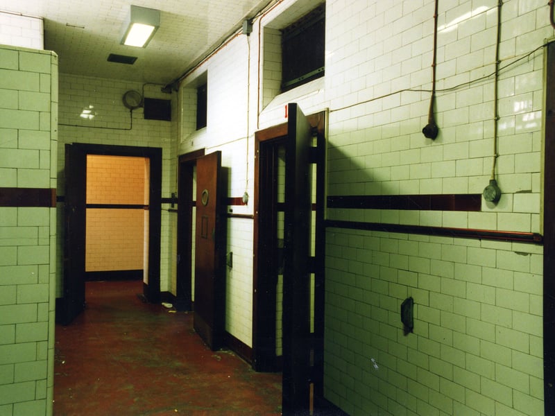 This photo taken in Van Gate Assembly of Leeds Bridewell.  Off camera, left, there is access to Oxford Place. Vehicles park at this entrance. The open doors lead to two cells, numbers 18 and 19. There is a short corridor through the doorway at the end accessing more cells.