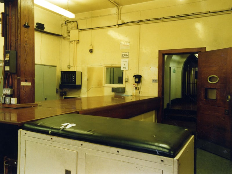 The Custody Officer's Room in the Leeds Bridewell. A prisoner would be brought in via this entrance, then down a long corridor to this room where details would be taken by the Custody Officer at this desk. The relevant documentation would be produced and the prisoner searched before being taken to a cell. This view looks through the open door to the corridor.