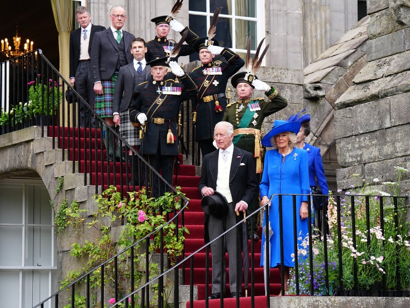 King Charles III and Queen Camilla, followed by the Princess Royal, stand on the steps as the national anthem is played as they arrive for the Sovereign's Garden Party at the Palace of Holyroodhouse in Edinburgh.