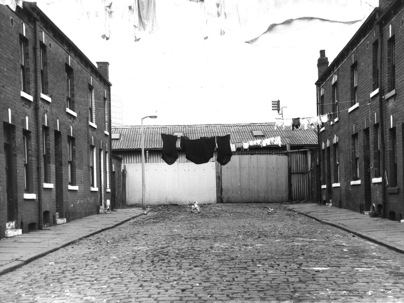 Marion Street in September 1971. On the left are odd numbered houses to the right. Several lines of washing hang across the street. In the centre is part of the premises of Saunders Valve Co Ltd with a corrugated iron wall.
