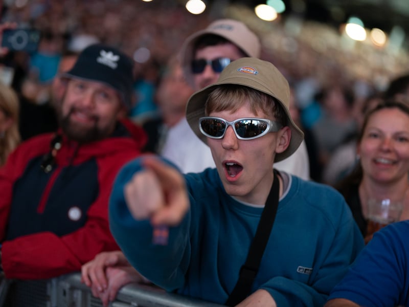 A fan in a bucket hat waits for Oasis to take to the stage at the Principality Stadium, Cardiff, as the band's long-awaited reunion tour kicks off in Wales. 			