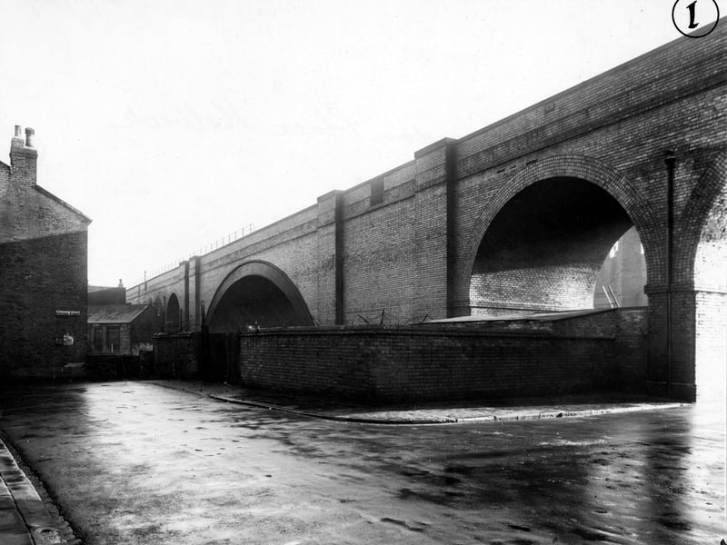 A view of Croydon Street showing Domestic Street Bridge and Croydon Place in November 1949. A brick wall with barbed wire surrounds the viaduct. A poster urges to use less water.