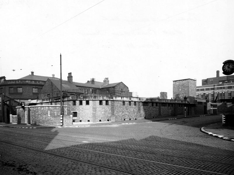 South Brook Street baths and washrooms, a low brick building. On the right is Simms Motor Units Ltd (their clock is just visible). Many of the corners of the walls, kerbs and posts have blackout markings on them. Tram lines are visible in the cobbled road. Pictured in October 1942.
