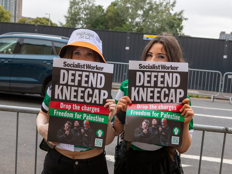 Two fans hold "Defend Kneecap" posters outside their gig at Glasgow's O2 Academy.