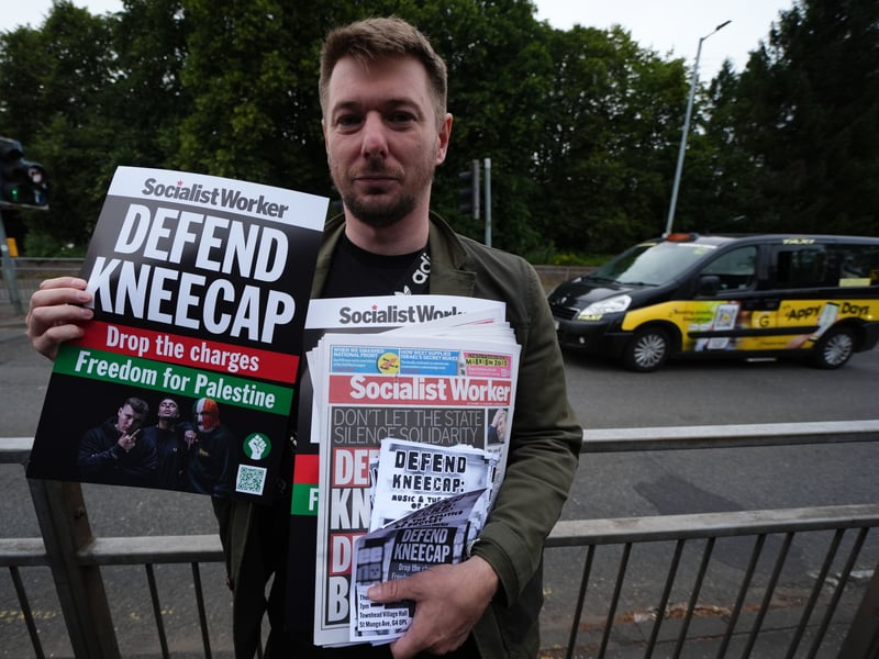 A fan holds Socialist Worker and 'Defend Kneecap' posters outside Kneecap's O2 Academy gig in Glasgow.