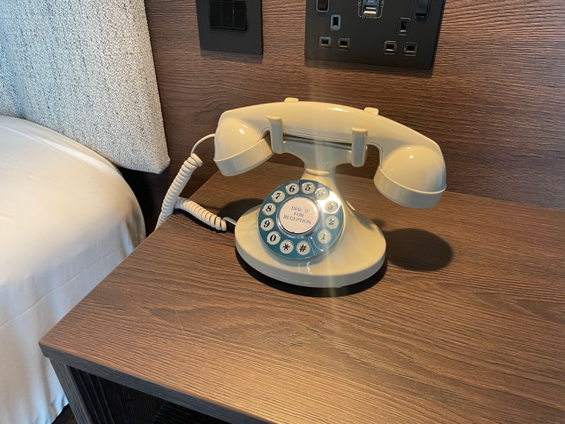 A retro phone sits elegantly on the bedside table.