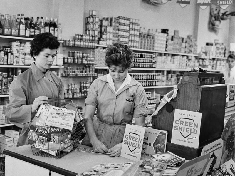 A shop assistant prepares to hand a sheet of Green Shield stamps to a customer at a newly opened supermarket in September 1960