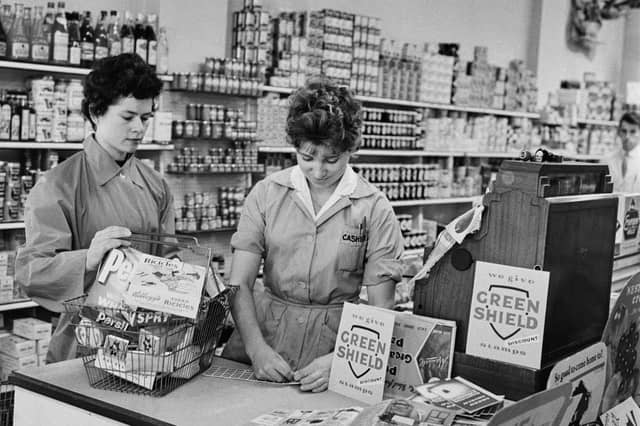 A shop assistant prepares to hand a sheet of Green Shield stamps to a customer at a newly opened supermarket in September 1960