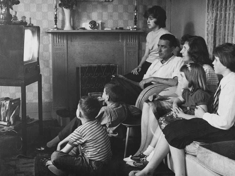 A family watching television together at home in September 1960