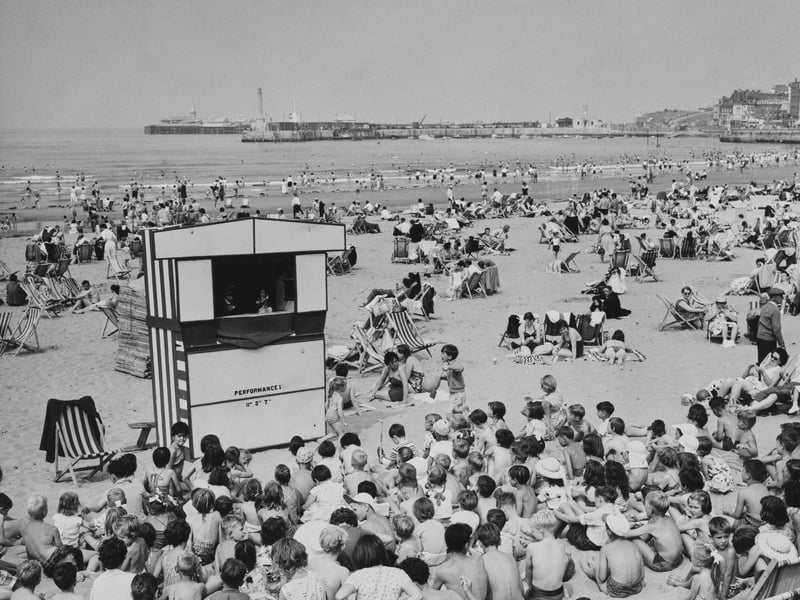 Holidaymakers watch a Punch and Judy show at the beach in Margate, Kent, in July 1961