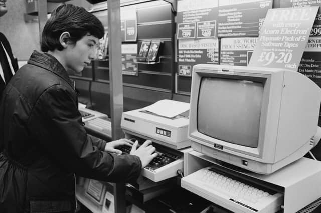 A young boy looking at Acorn Electron computer and monitor in a WHSmith shop in Waterloo, London, in December 1984