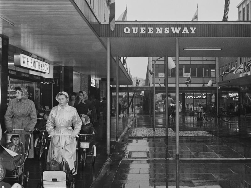 Shoppers pass the WH Smith & Son store at Queensway shopping centre in Stevenage on a rainy day in April 1959