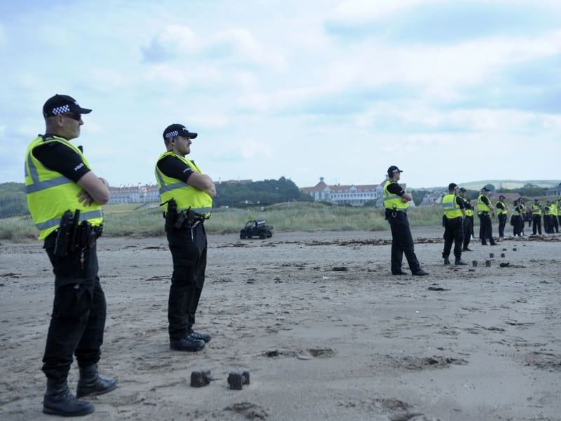Police officers keep an eye on a group of protesters on the beach next to Trump Turnberry.