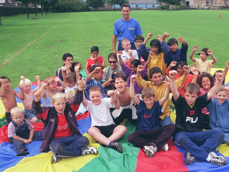 Children pictured at the Coleridge Road playing fields,
where Community Recreation Sheffield City Council and the Out of School Network were holding their children's playscheme in August 1999. They are seen with Mr Goddard, one of the scheme organisers.