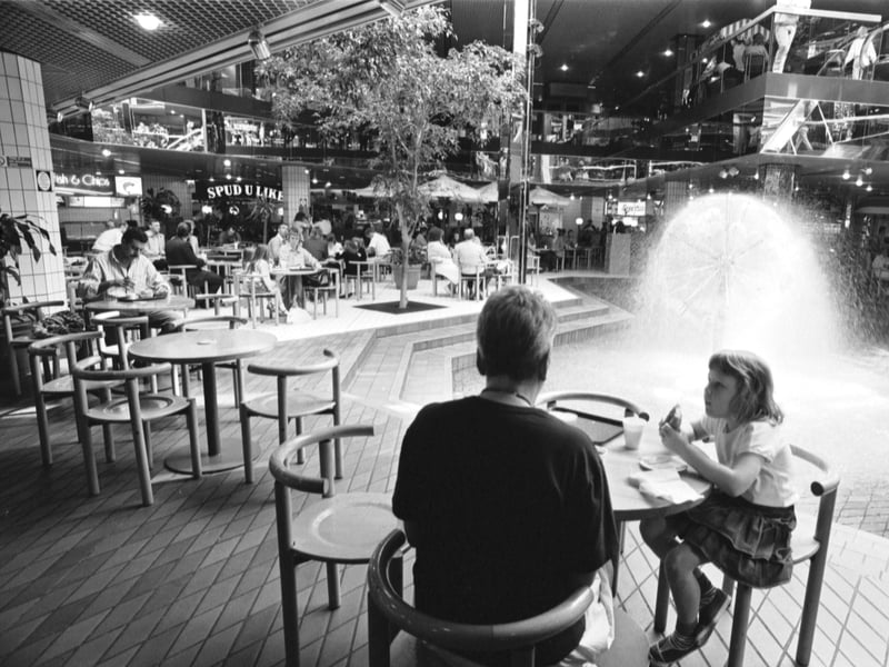 People eating in the Food Court at Waverley Market shopping centre, Edinburgh, with the fountain in the centre, in July 1988