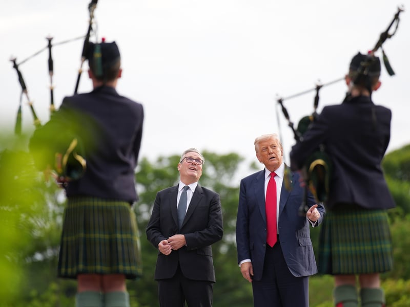 U.S. President Donald Trump and British Prime Minister Keir Starmer stand in front of some people playing the bagpipes at Trump International Golf Links on July 28, 2025 in Balmedie, Aberdeenshire, Scotland.