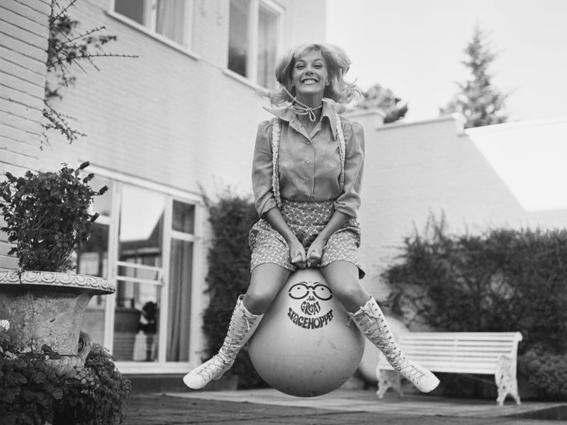 British actress and dancer Aimi MacDonald bounces on a Space Hopper in the garden in September 1970
