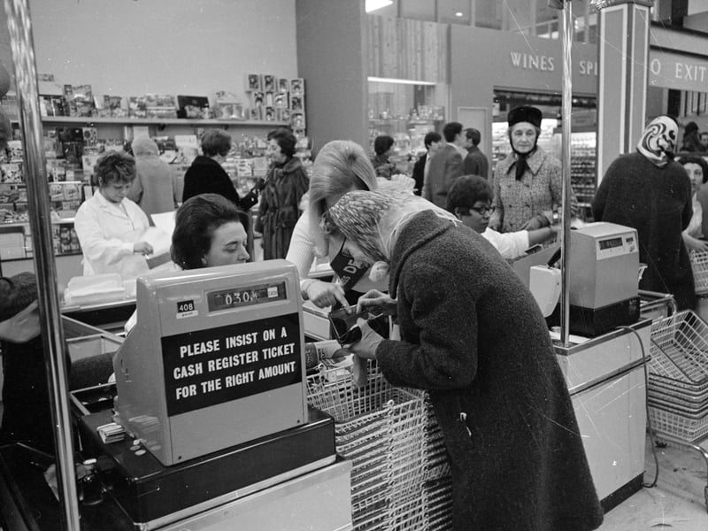 A supermarket assistant helps an elderly customer pay for her purchases using the new coins on the first day of national decimalisation, February 15, 1971