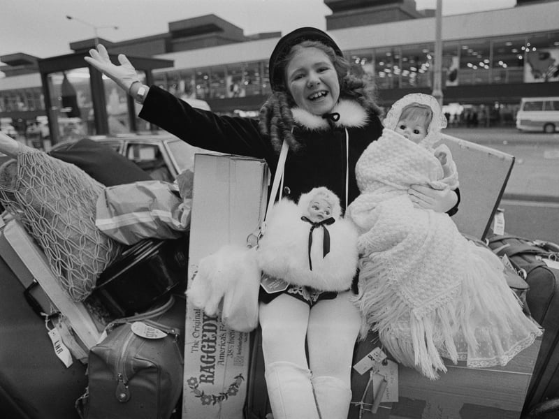 Young actress Bonnie Langford sits on a stack of suitcases with her dolls in January 1975