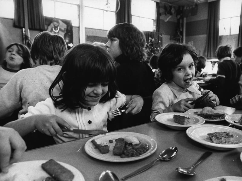 Pupils enjoy their school dinner of fish fingers, baked beans and potato, with sponge and custard to follow, in December 1974