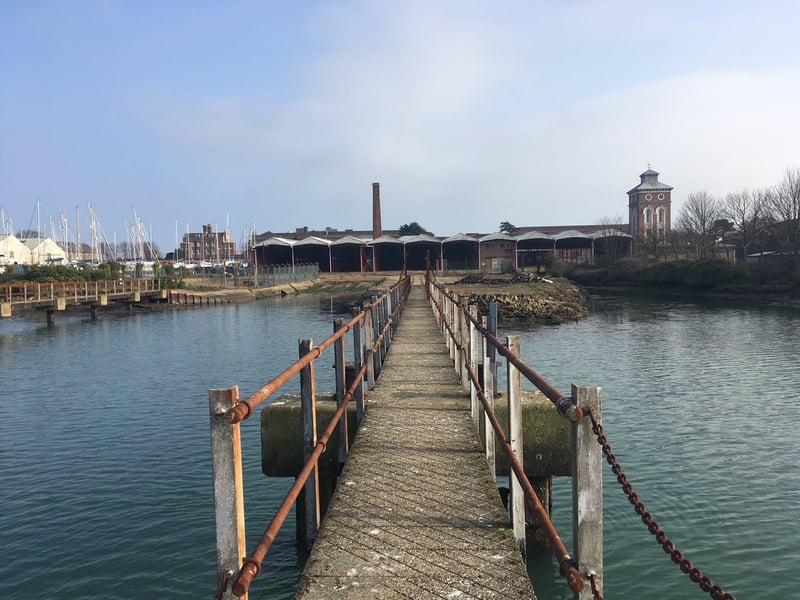 A row of ten gunboat sheds and three maintenance workshops, designed in 1856 by William Scamp of the Admiralty Works Department as part of the Haslar Gunboat Yard for the housing and repair of British gunboats, and their successor craft, of the Royal Navy. The adjacent traverser system was used for their launch and movement. The site ceased to be used in the mid-1970s but remained in MOD ownership. Once vacant, its condition deteriorated, with only minimum maintenance undertaken. Historic England grant aided a feasibility study in 2019 to help find an appropriate new use for the site. It has been given a priority C grade and is in "very bad" condition.