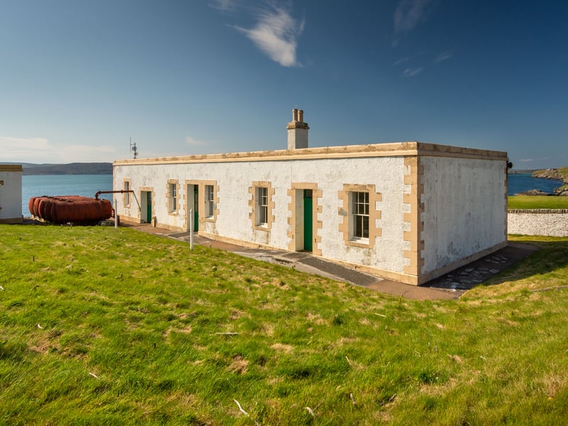 The complex includes a pair of semi-detached, single-storey cottages within a stone-built structure, with pitched slate roofs