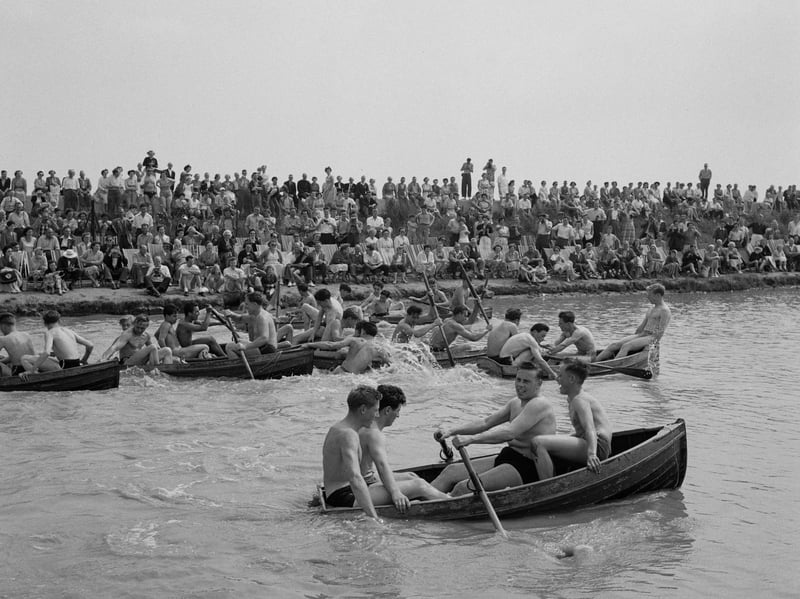 A crowd watches men in their swimwear rowing boats at Butlin's Holiday Camp, Clacton-on-Sea, Essex, in August 1956