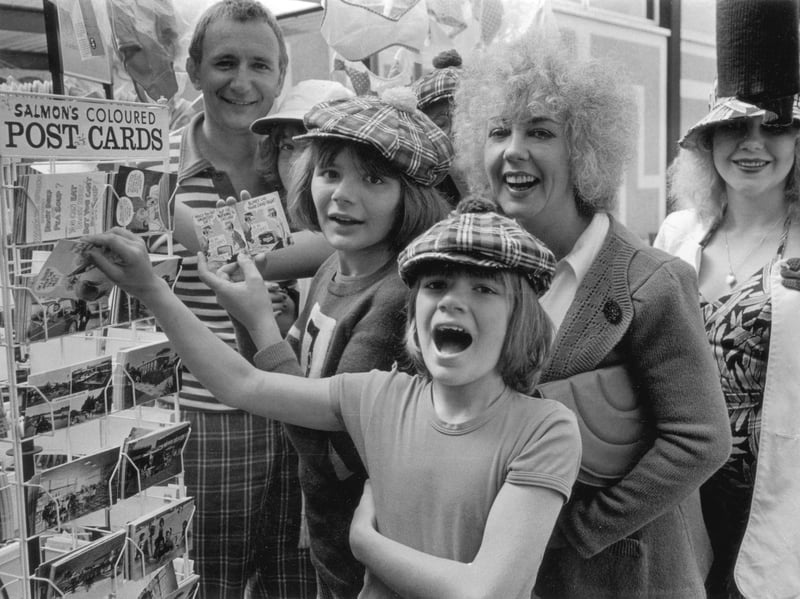 British writer Molly Parkin and her husband, artist Patrick Hughes, with their children at Butlin's in August 1974, perusing a selection of postcards