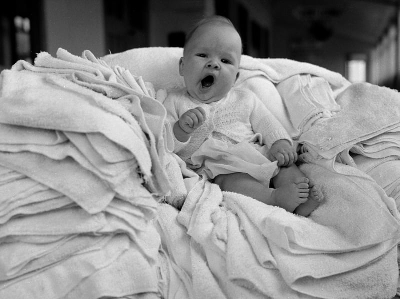 A baby rests on a pile of nappies in the laundry room at Butlin's Holiday Camp in Clacton-on-Sea, Essex, in September 1961