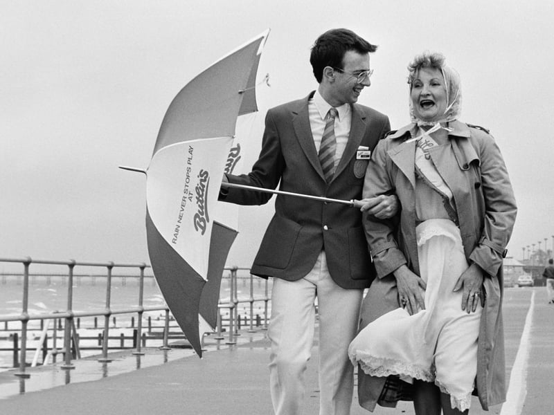 A Redcoat and the winner of the camp's glamorous grandmother competition walk along the seafront near to the Butlins Holiday Camp in Bognor Regis, West Sussex, in June 1985