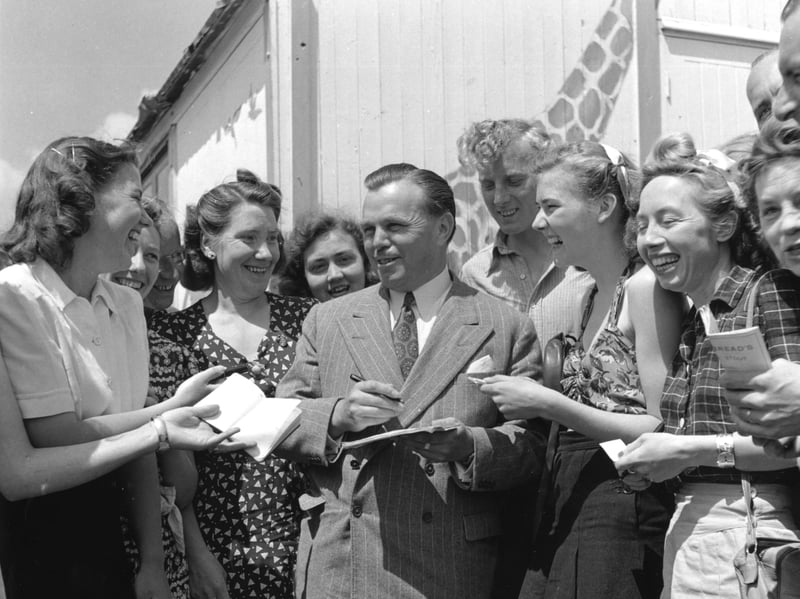 Billy Butlin, the director of Butlin's holiday camps, is surrounded by autograph hunters in July 1947